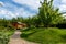 Scenic view yard garden trees and paved stone path road for walk against beautiful blue sky. Landscape design green lawn