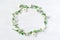 Scenic wreath of white flowers on white wooden background