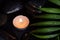 Scent lighted candle on black wet stones and green leaf with droplets, dark photography