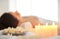 Scented candles, flowers and relaxed woman in spa salon