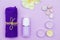 Scented candles, towel, lotion and pebbles on a lilac background