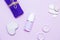 Scented candles, towel, lotion and pebbles on a lilac background