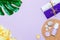 Scented candles, towel, lotion, pebbles and monstera leaf on a lilac background