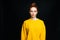 Sceptic disgruntled young woman wearing yellow sweater posing on isolated black background