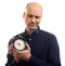 Sceptical bald man holding an alarm clock