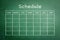 Schedule with grid timetable on green chalkboard