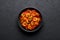 Schezwan Prawns in black bowl at dark slate background. Schezwan Prawns is indo-chinese cuisine curry dish