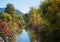 Schlierach river with colorful autumnal trees and shrubs at the riverside