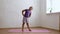 School age girl in sportswear standing and sluggishly bending body sideways on gymnastic mat in empty room, free copy