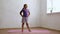 School age girl in sportswear standing and sluggishly and too slow bending body sideways on gymnastic mat in empty room
