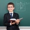 School boy with book, archimedes principle drawing on chalkboard background, dressed in classic black suit, education concept
