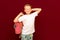 School boy coffin on the back of the head with backpack, on red wall