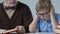 School boy covering his ears ignoring grandfather explaining him boring subject