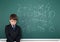 School boy decides examples math wrong on chalkboard background, education concept