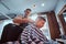 School boy is enjoing the process of haircut from expirienced barber at modern barbershop.