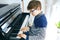 School boy with glasses playing piano in living room. Child having fun with learning to play music instrument. Talented