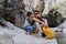 School boy and his dad with yellow backpack sits on a riverside rock in the canyon with mountain cliffs in the