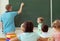 School boy with his teacher at the blackboard at math lesson in classroom at school