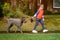 School boy pulls dog outdoors. Funny dog walker training to walk on leash without pulling. Take care of animal. Kid with