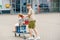 A School Boy Pushes the Cart While a Preschool Girl Happily Sits Inside, as They Enjoy a Fun Family Shopping Trip. Happy