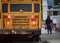 School bus with flashing lights and children boarding diffused in the distance