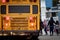 School bus with flashing lights and children boarding diffused in the distance