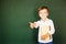 School child thumbs up and hold book over blackboard. Free text, copy space