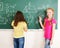 School child writting on blackboard.