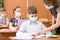 School children with protective masks against coronavirus at lesson in classroom