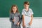 School children siblings hold book with surprising expression against blackboard. School kids friends.