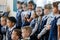 School. Cool room. Children in school uniform stand in two rows and pose for another photographer. One girl got distracted and