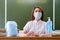 The school doctor sits in the classroom and distributes medical masks. School nurse handles hands with a sanitizer, copy space