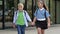 School friendship. A boy and a girl, primary school students, walk out of the school building holding hands.