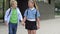 School friendship. A boy and a girl, primary school students, walk out of the school building holding hands.