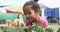 In a school garden, a young biracial student examines flowers with a magnifying glass