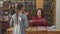 A school girl with pigtails stands in front of a woman teacher or librarian