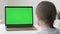 School girl studying during online lessons in front of green screen laptop, back view