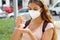 School girl wearing KN95 FFP2 mask using hand sanitizer in city street