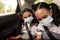 School girls sitting in car with face mask and seat belt