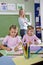 School girls writing in notebooks with teacher