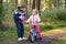 School kid boy, brother put on little preschool sister girl bike helmet on head. Brother teaching happy child cycling