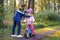 School kid boy, brother put on little preschool sister girl bike helmet on head. Brother teaching happy child cycling