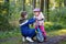 School kid boy, brother put on little preschool sister girl bike helmet on head. Brother teaching happy child cycling