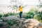 School kid child in vibrant clothes jumping over granite rock boulders in the city park with mountain forest view in the