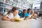 School kids lying on floor reading book in library