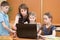 School kids and teacher at laptop in the classroom