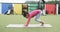 In a school playground, a young Hispanic girl practices yoga