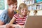 School Pupil With Teacher Using Laptop Computer In Classroom