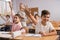 School pupils raise their hands up in classroom