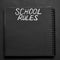 School rules word written on a notepad with blank space. Blank black notepad background